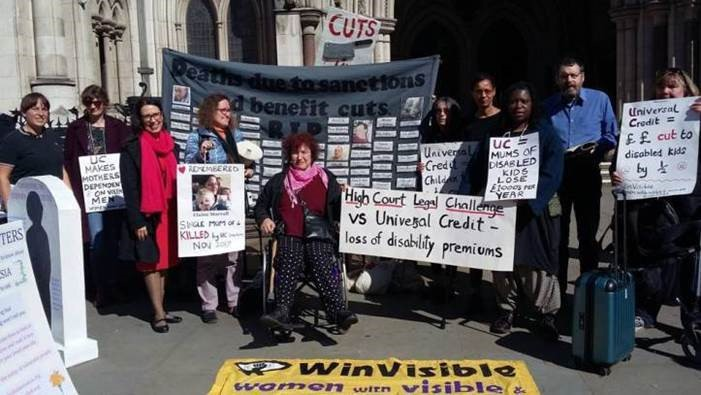 Women and men outside the High Court holding placards.  A grey banner: "Deaths due to sanctions and benefit cuts" with the names sewn on of people who died. "High Court Legal Challenge vs Universal Credit -- loss of disability premiums."  Universal Credit = money cut to disabled kids by half.  WinVisible banner on pavement.